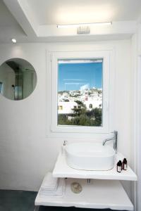 Villa Loom Mykonos Town في مدينة ميكونوس: حمام مع حوض أبيض ونافذة