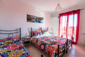 a bedroom with a bed with colorful sheets and a window at New Naxos Village in Giardini Naxos
