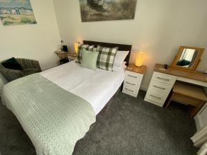 1 dormitorio con cama y escritorio con espejo en Coach Guest House, en Tenby