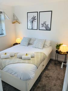 two beds in a bedroom with two pictures on the wall at Spacious House, Free Parking & Patio Garden in Farnham