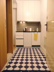 uma cozinha com armários brancos e um piso xadrez em Super Central & Panoramic Nick's Apartment em Pristina