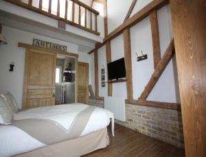 1 dormitorio con 1 cama y TV en la pared en La Haute Muraille, en Saint-Folquin