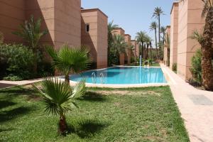 a swimming pool in front of a building with palm trees at Résidence alqaria assiyahiya full private riad in Marrakech