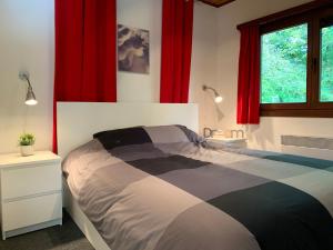 een slaapkamer met een bed met rode gordijnen bij Clos des Chevreuils - Le Chalet in Barbençon