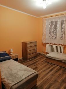 a bedroom with two beds and a dresser and a window at Apartament Reymonta in Łowicz