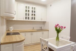 a kitchen with white cabinets and a vase of flowers on a table at VIP- Elite Lemberg Apartments in Lviv +8 photos