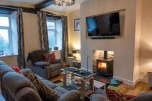 a living room with a fireplace and a tv at High Gregg Hall Farm Cottage in Underbarrow