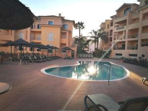 a swimming pool in a resort with chairs and umbrellas at Praia da Luz Monique Apartment in Luz