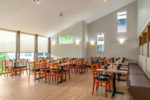 een restaurant met houten tafels, stoelen en ramen bij Holiday Inn Cape Cod - Hyannis, an IHG Hotel in Hyannis