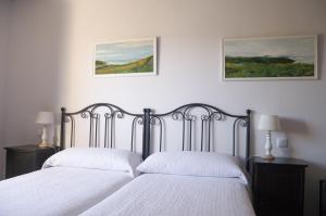 two beds in a bedroom with two pictures on the wall at Apartamentos Corona in Comillas