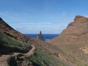 a group of people walking on a dirt path between two mountains at Casa Shalom in Faial