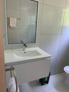 uma casa de banho branca com um lavatório e um espelho em Kura's Kabanas em Rarotonga