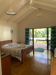 een slaapkamer met een bed en een glazen schuifdeur bij Kura's Kabanas in Rarotonga