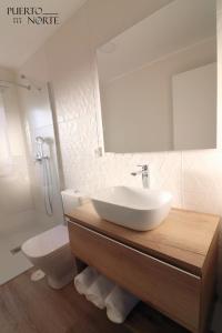 a bathroom with a sink and a toilet and a mirror at Apartamentos Puerto Norte - Apto 3 in Puerto de Vega +13 photos