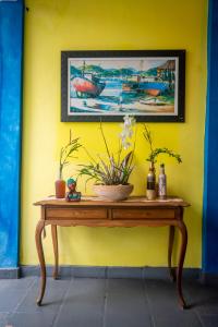 uma mesa com flores em cima de uma parede amarela em Pousada Salvatore em Arraial do Cabo