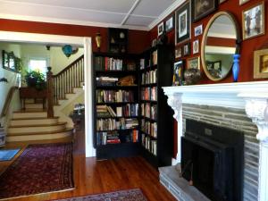 a living room with a fireplace and a book shelf filled with books at Cooperstown Bed and Breakfast in Cooperstown