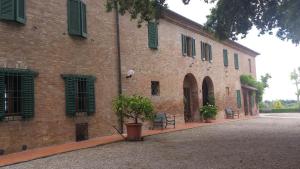 a brick building with chairs and a tree in front of it at Agriturismo Il Poggiarello in Siena