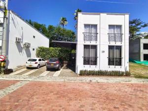 a white building with two cars parked in front of it at Villas del Guali - Piscina Privada in Santa Fe de Antioquia