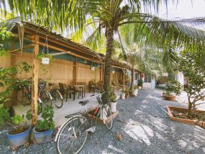 a bike parked in front of a building with palm trees at Mecong Homestay in Ben Tre