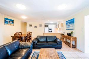 a living room with a leather couch and a table at Oceania 11 - LJHooker Yamba in Yamba
