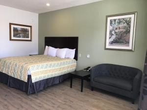 Habitación de hotel con cama y silla en Big Lake Inn and Suites, en Big Lake