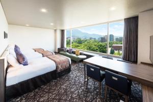 札幌市にあるホテルマイステイズ札幌中島公園のベッド、デスク、大きな窓が備わるホテルルームです。