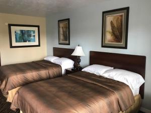 a hotel room with two beds and a lamp at Immokalee Inn in Immokalee
