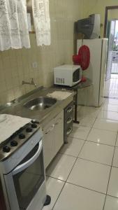 a kitchen with a sink and a stove and a microwave at ILHA DOS CORAIS -Ap 304 C in Balneário Praia do Leste