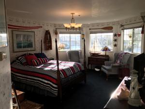 a bedroom with a bed and a chair and windows at Marina Street Inn in Morro Bay