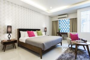 1 dormitorio con 1 cama con almohadas rosas y verdes en Tolani Nimman Villa Chiang Mai, en Chiang Mai