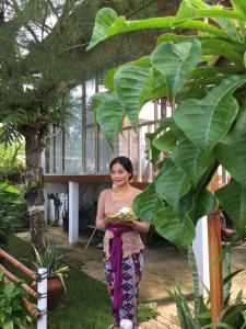 a woman standing in a garden holding a plate of food at my house guest house in batumadeg