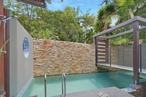 a swimming pool in front of a brick wall at Tree Top Oasis in Buderim