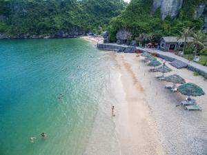 a beach with umbrellas and people swimming in the water at Cat Ba My Ngoc View Hotel in Cat Ba