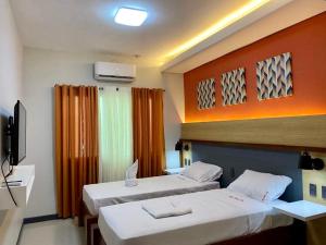 a hotel room with two beds and a television at Kara’s Pension House in Tuguegarao City