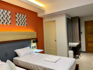 een slaapkamer met een bed met een oranje muur bij Kara’s Pension House in Tuguegarao City