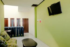 Cette chambre dispose d'un canapé et d'une télévision murale. dans l'établissement Zulfina Homestay Syariah Mitra RedDoorz, à Banyuwangi