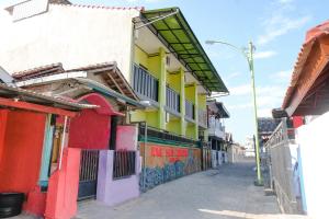 a row of buildings on a street with graffiti at Zulfina Homestay Syariah Mitra RedDoorz in Banyuwangi