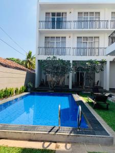 two people standing next to a swimming pool in front of a building at The Suite 262 in Negombo