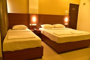 2 letti in una camera d'albergo con pareti gialle di Hotel Citywalk Residency a Mangalore