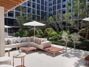 eine Terrasse mit einem Sofa, Tischen und einem Sonnenschirm in der Unterkunft D2 residences huahin 华欣市中心近海滩近商场酒店式公寓可加床有连通房型 in Hua Hin