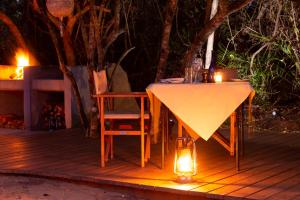 a table and chairs on a deck at night at Gugulesizwe Camp in Mabibi