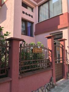 a pink building with a fence with a sign on it at Guest House Dara in Tsarevo