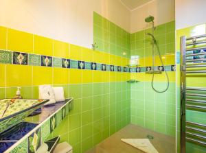 a bathroom with green and yellow tiles and a shower at Penta Apartments in Gamlitz