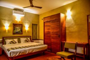 ein Schlafzimmer mit einem Bett, einem Schrank und einem Stuhl in der Unterkunft Chembra Adobe in Kalpatta