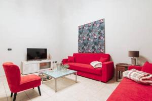 uma sala de estar com dois sofás vermelhos e uma televisão em Flores Home em Bari