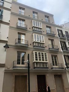 a building with balconies and a woman standing in front of it at Pinar Malaga Rooms in Málaga