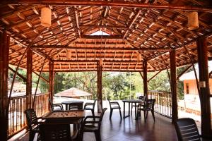 einen Holzpavillon mit Tischen und Stühlen auf einer Terrasse in der Unterkunft Chembra Adobe in Kalpatta