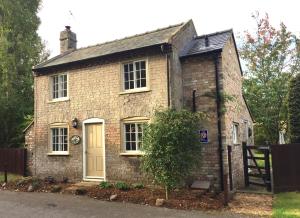 a small brick house with a tree in front of it at The Old Post Office, Hilton in Huntingdon