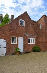 a brick house with two white doors and two windows at Norfolk Broads Bolthole in Stokesby