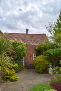a brick house with a bench in front of it at Norfolk Broads Bolthole in Stokesby